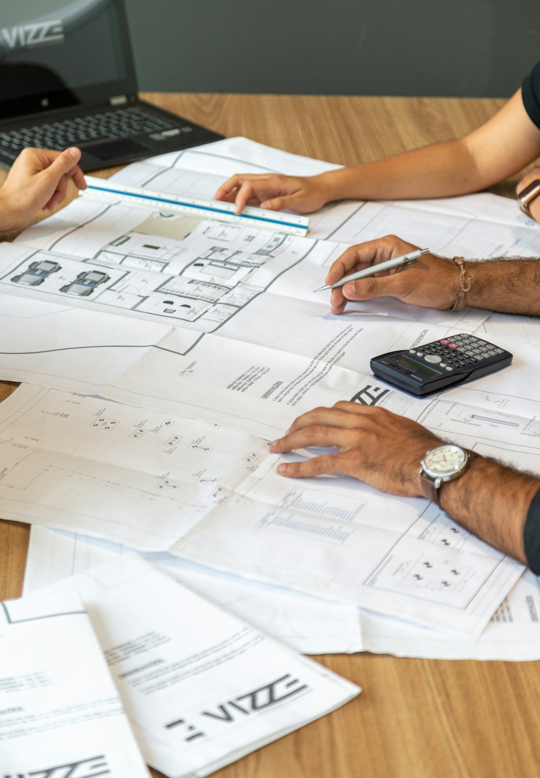 people-reviewing-architectural-blueprints-on-desk-3qzmbrvceyq
